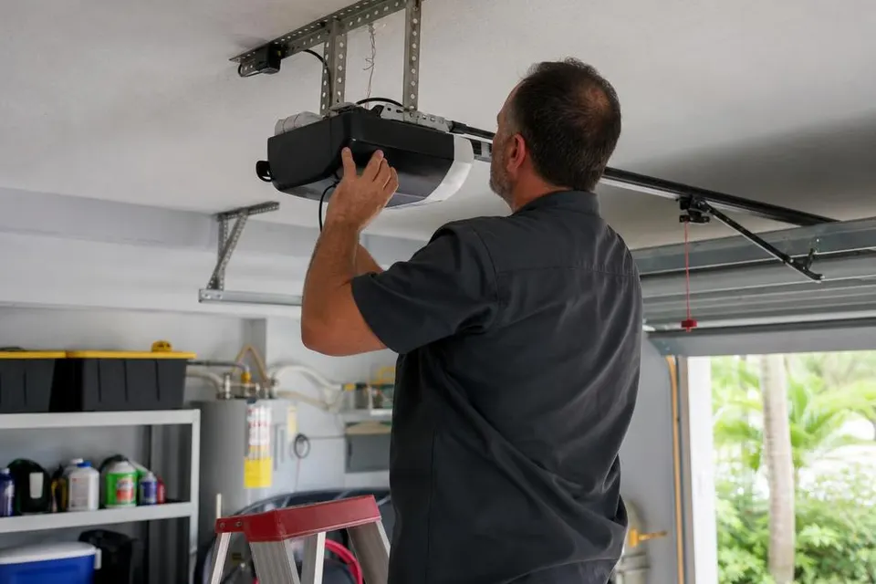 Technician inspecting a ceiling-mounted garage door opener
